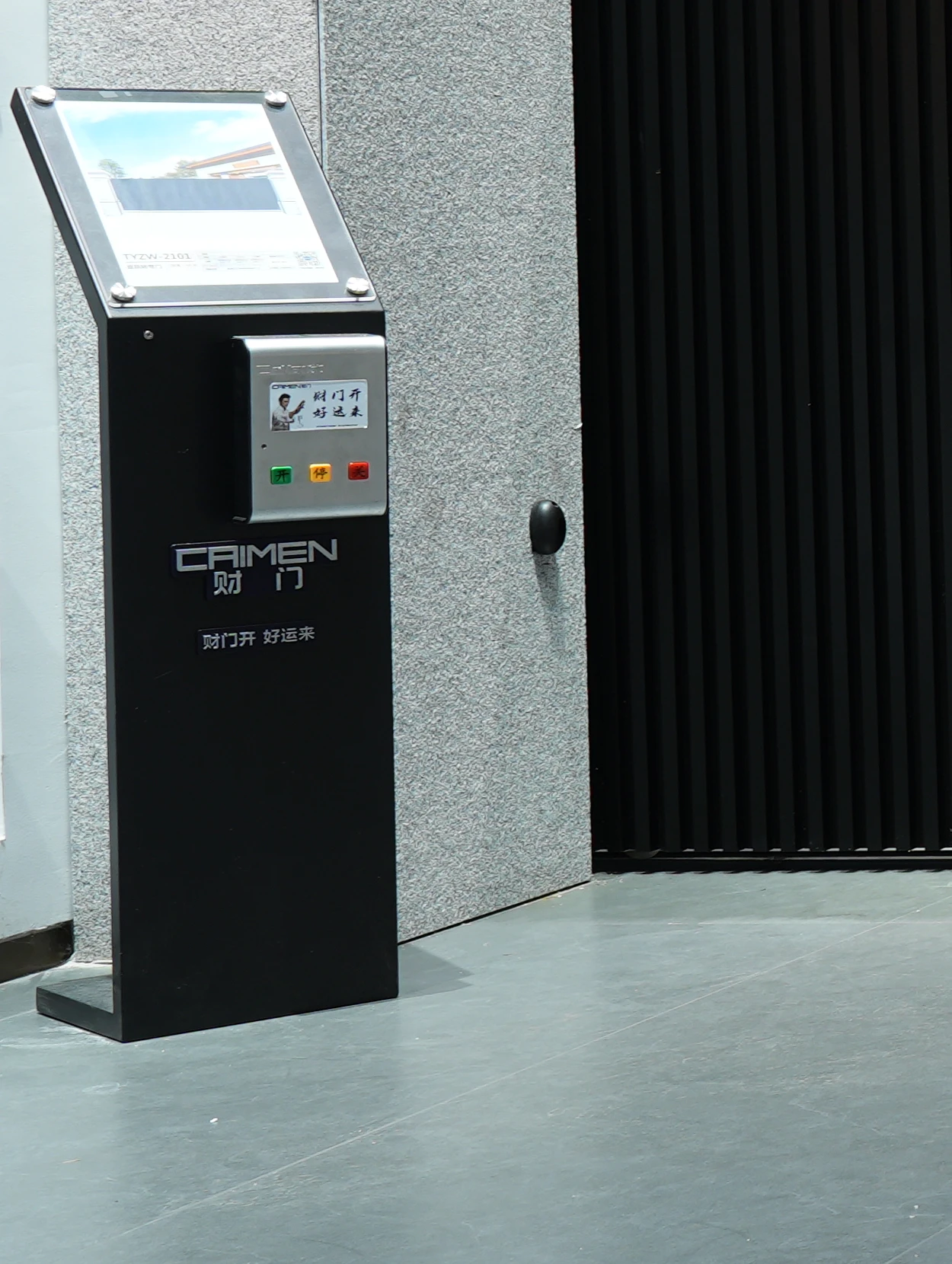 Entrance control terminal beside a CAIMEN sectional gate.