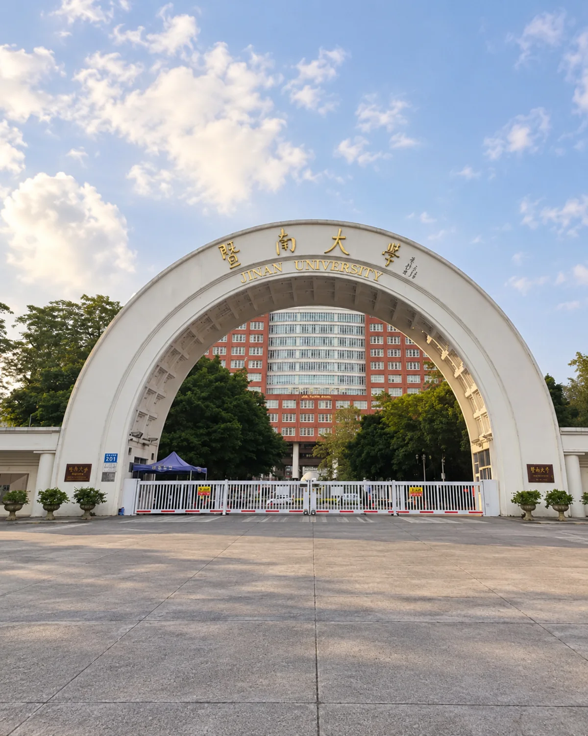 White telescopic entrance gate beneath the Jinan University gateway.